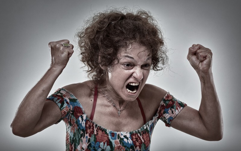 Angry senior woman yelling and raising her fists