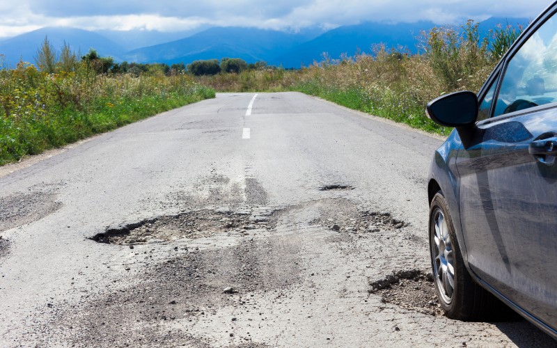 car and cracked asphalt with holes in the road