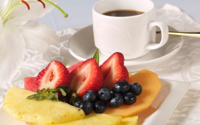 plate of fruits with cup of black coffee