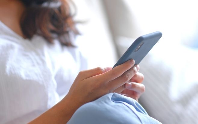 woman sitting on couch using cellphone