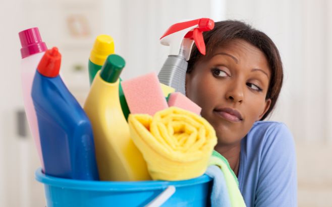 Black woman holding cleaning supplies