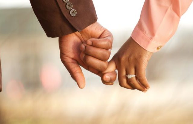 couple holding fingers while walking