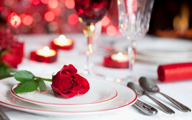 rose on dinner plates surrounded by silverware