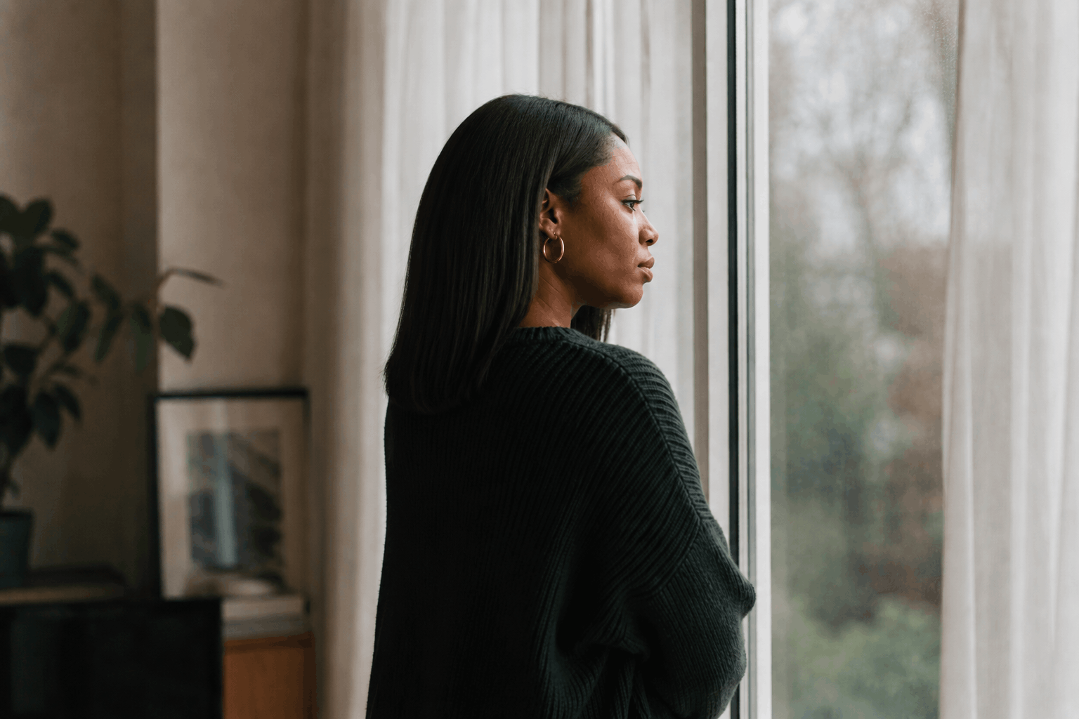 Black woman standing looking out the window